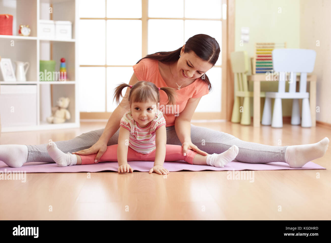 Mother and child daughter doing fitness exercises on mat at home Stock Photo