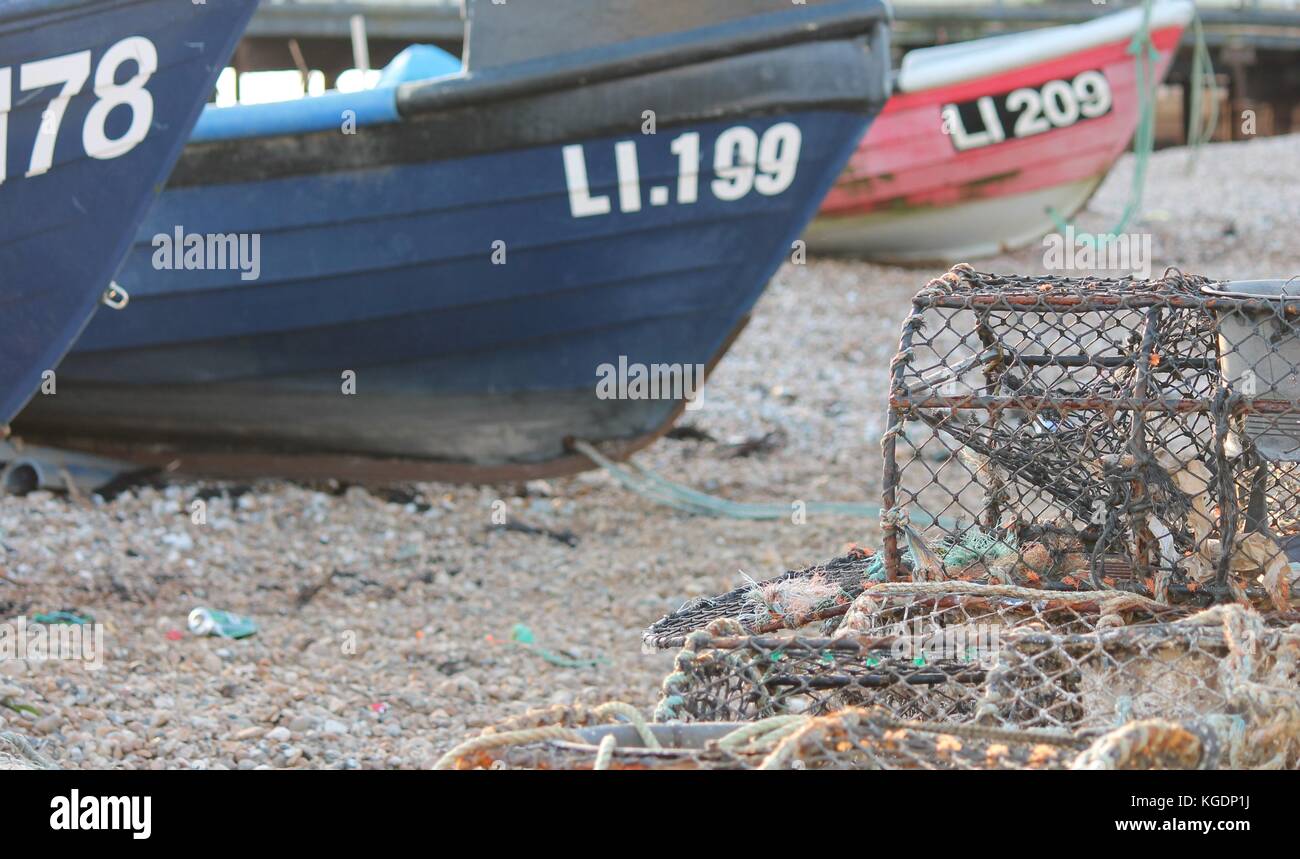 Fishing boat on pebble beach shore with lobster pot traps Stock Photo