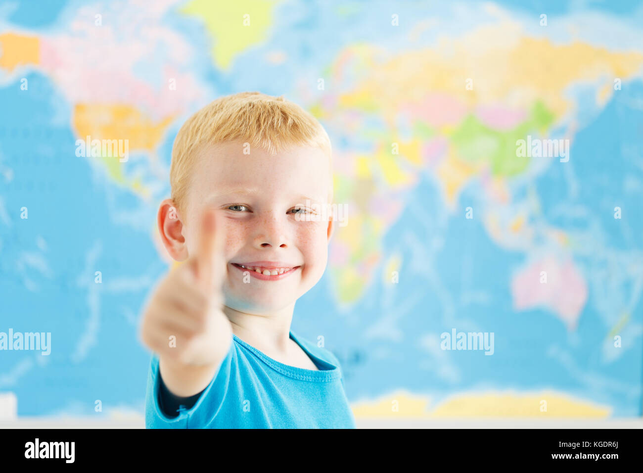Happy boy showing thumbs up gesture in a classroom of geography Stock Photo