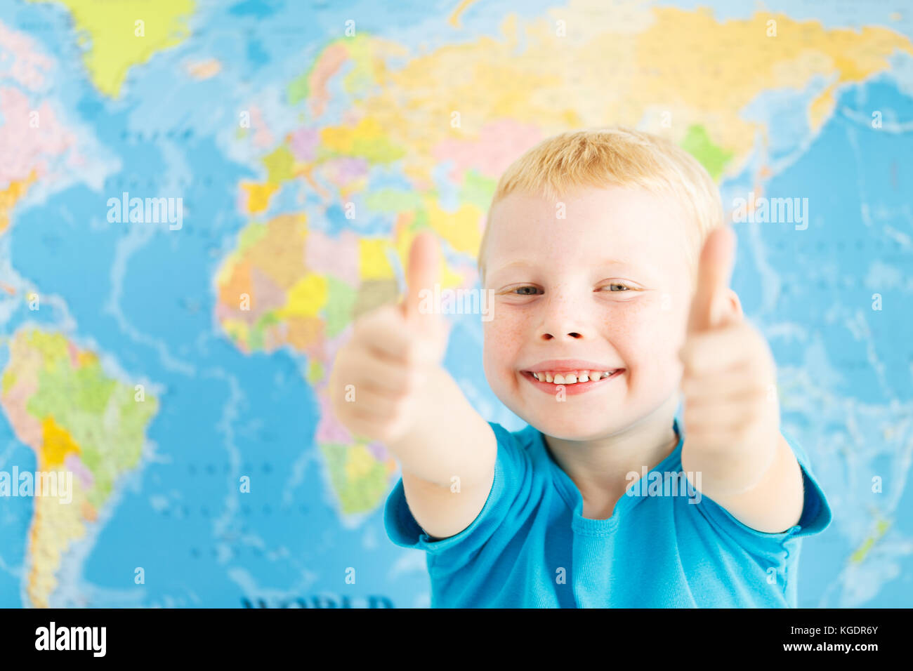 Happy boy in a classroom of geography showing thumbs up Stock Photo