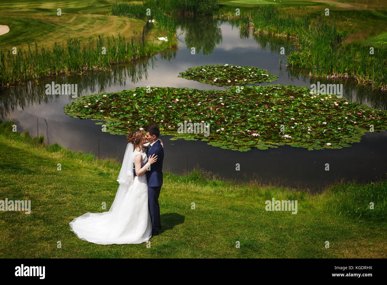 Beautiful bride and groom kissing and hugging near lake Stock Photo - Alamy