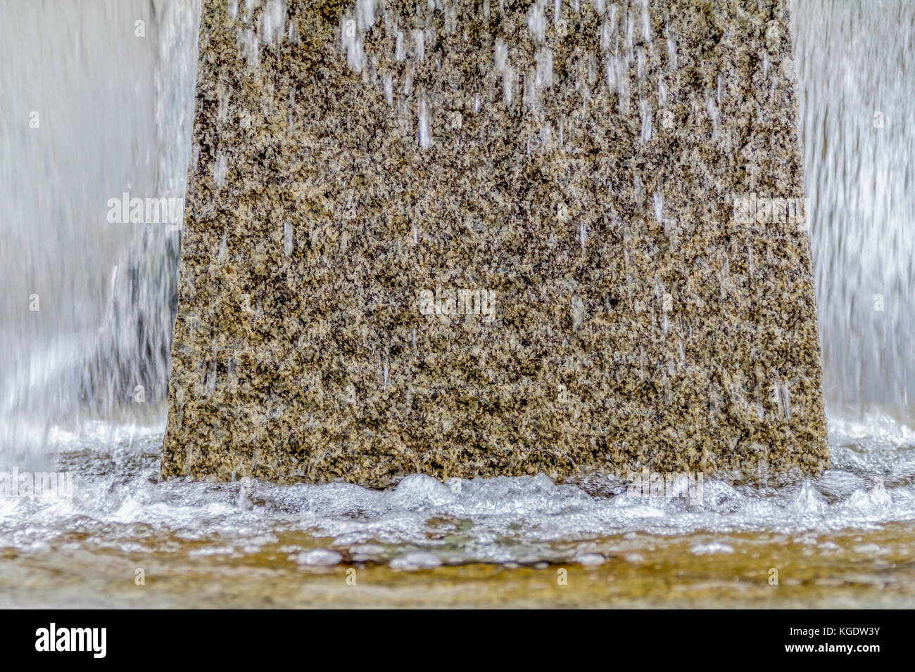 waterspout fountain detail including a water surface with small waves, water drops and splashes in stony ambiance Stock Photo