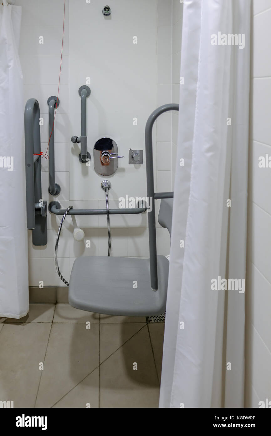 Disabled shower in the changing room. Shows hand rails and seat with white curtain. Stock Photo