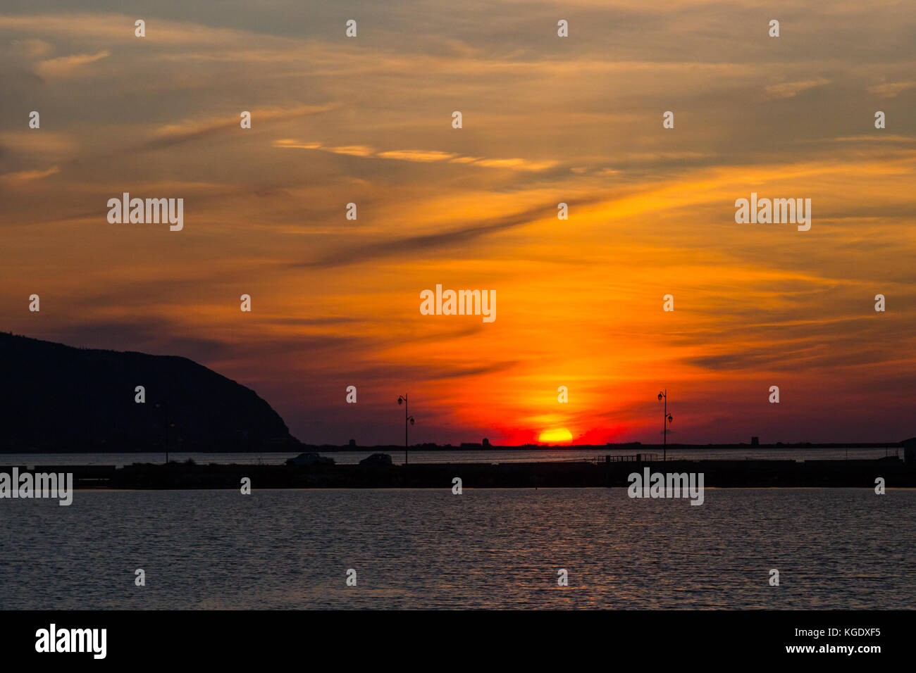 natural sunset at lefkas lagoon in greece with dike and water, streetlamps Stock Photo