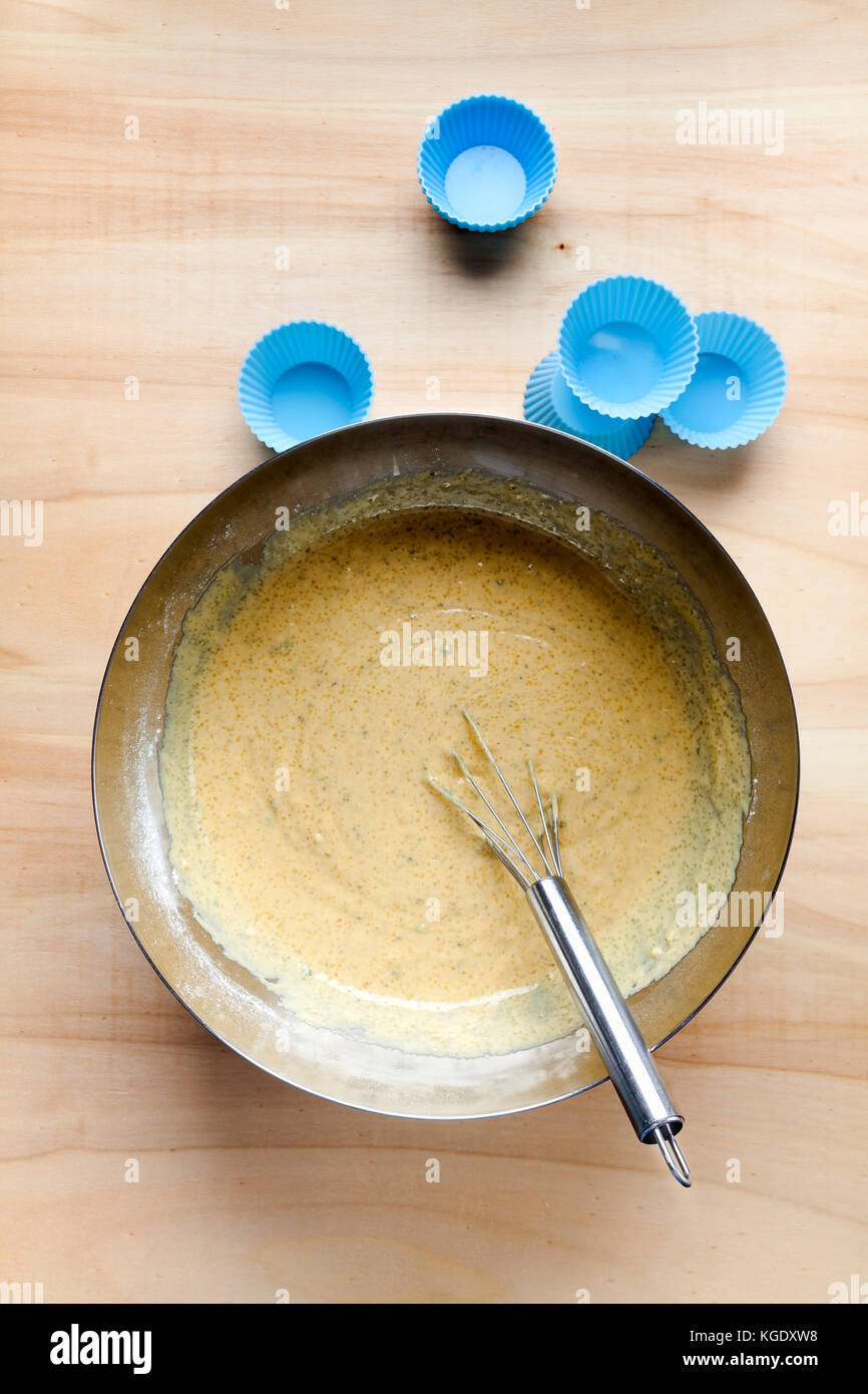 in a large metal bowl, a ready-made batter and whisk for muffins and silicone molds Stock Photo