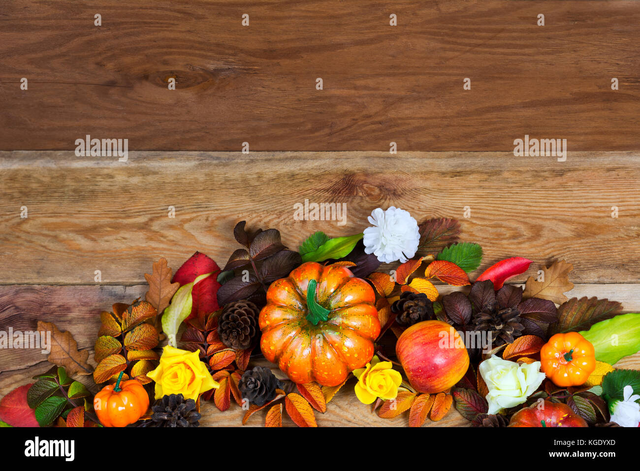 Thanksgiving table centerpiece with pumpkins, apples, pine cones, colorful fall leaves, yellow roses and white flower on the rustic wooden background, Stock Photo