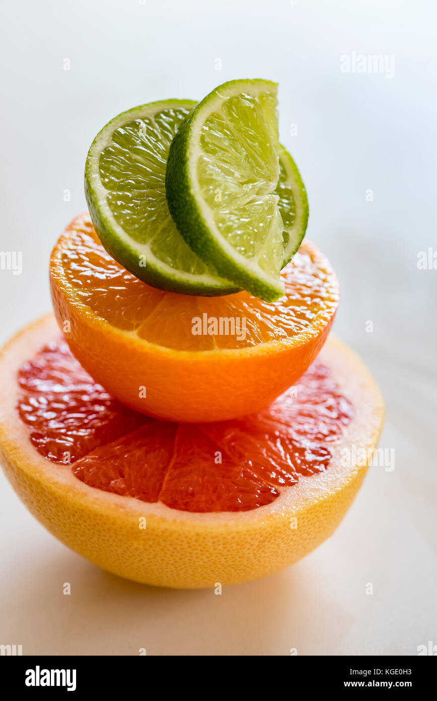 Colorful pile of half citrus fruit, top view, macro. Grapefruit, orange and lime fruit halves, macro, vertical. Stock Photo