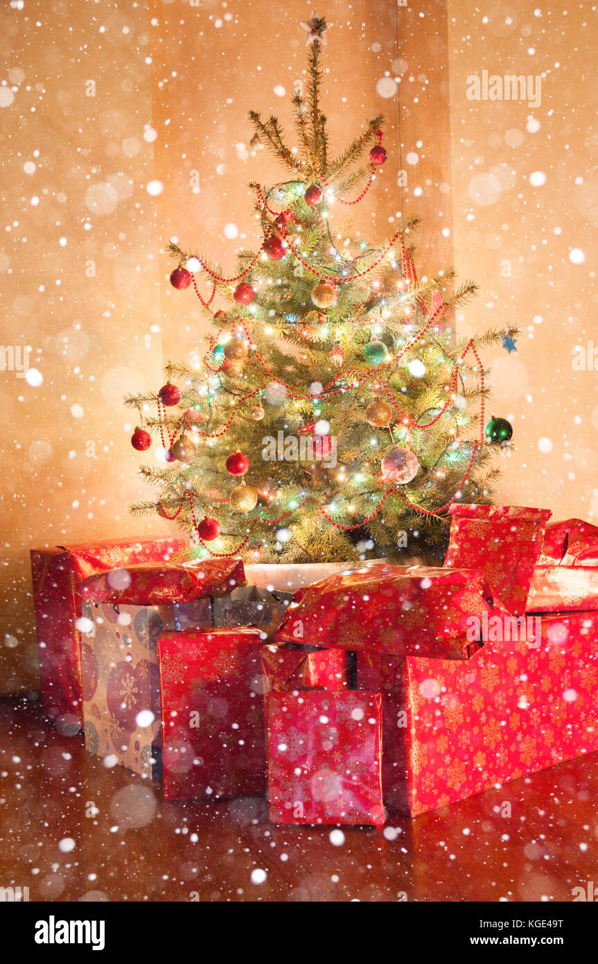 Christmas tree with lights and presents in dark room Stock Photo