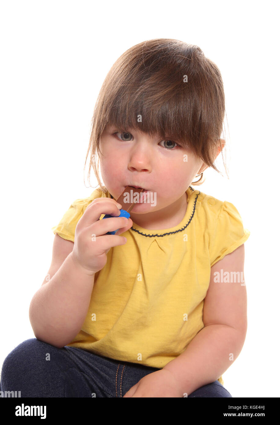 two year old girl eating chocolate in studio Stock Photo