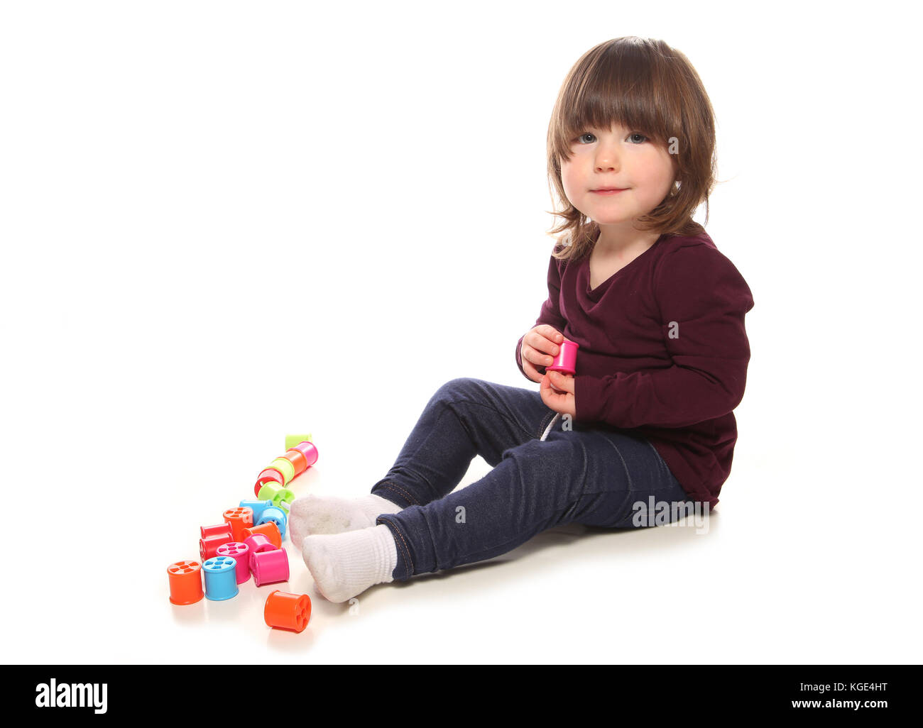 two year old girl playing with cotton reels in studio Stock Photo