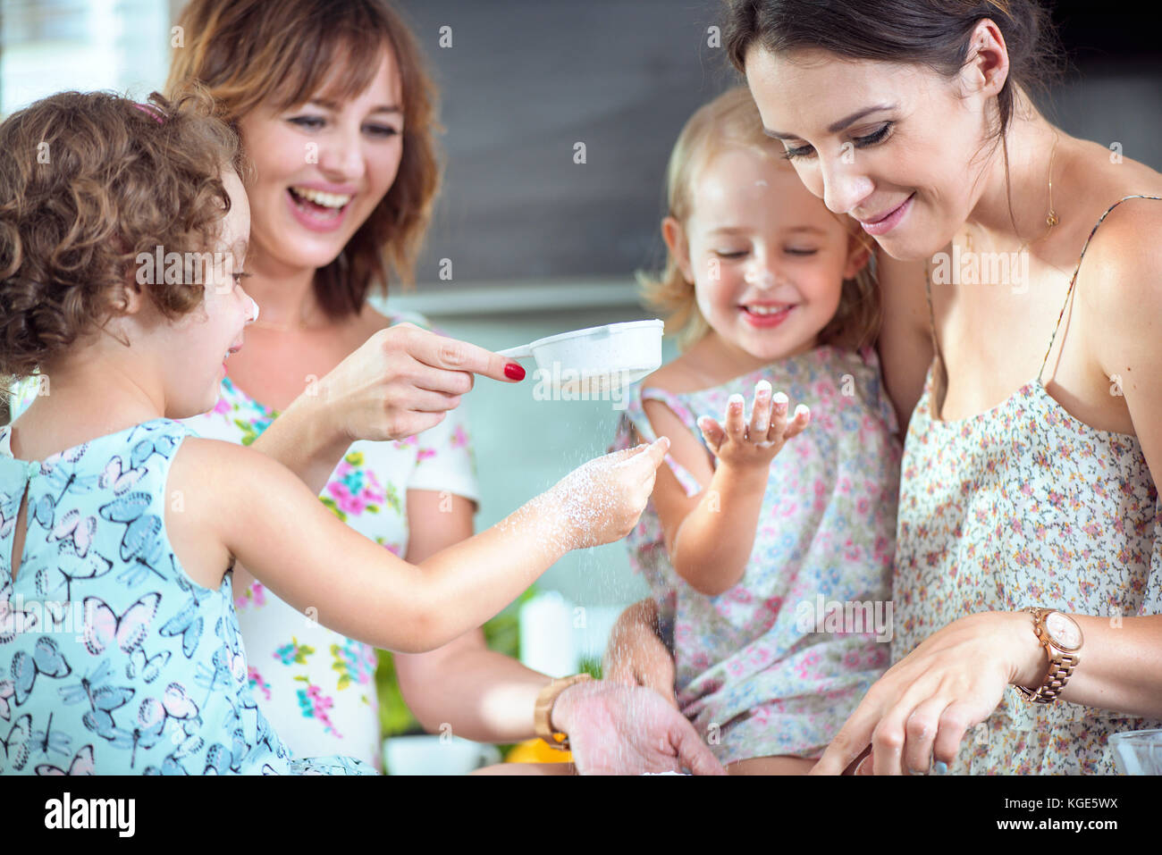 Two Mothers And Their Daughters Baking A Summer Light Cake Stock Photo Two mothers and their daughters baking a summer light cake stock photo