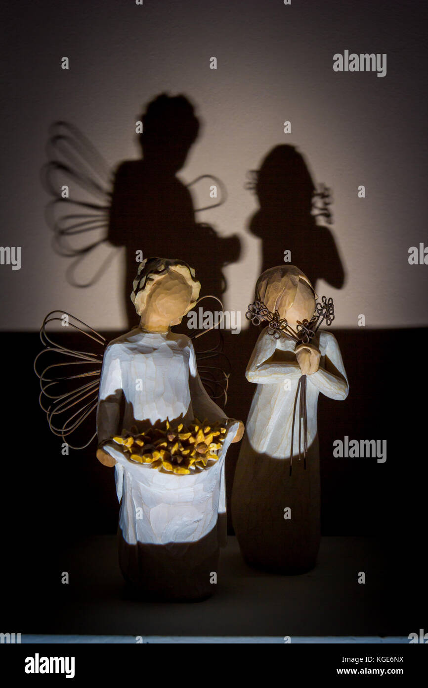 A pair of Willow Tree Figurines by Susan Lordi posing together with a strong shadow of the