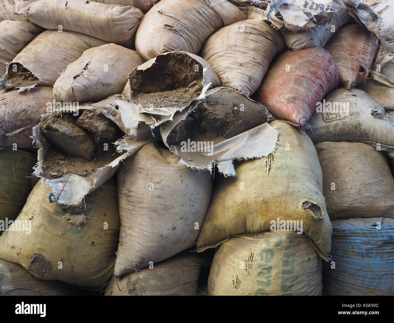 The old torn linen bags with rubbish lie in pile, the ground and straw