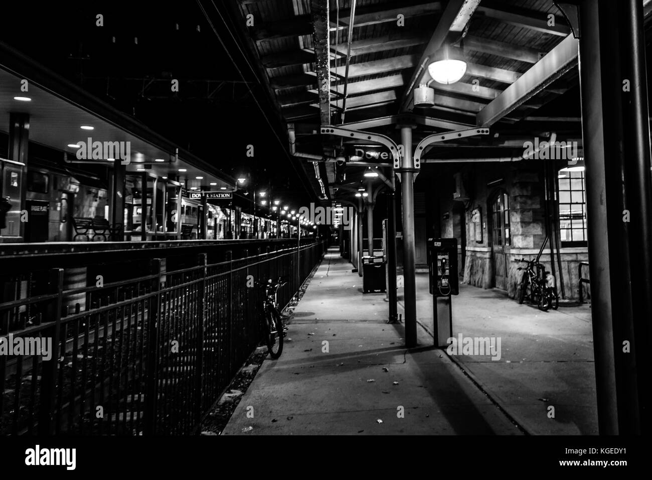 Dover, NJ USA - November 2, 2017:  Bicycles rest along the grungy train station at night, black and white Stock Photo