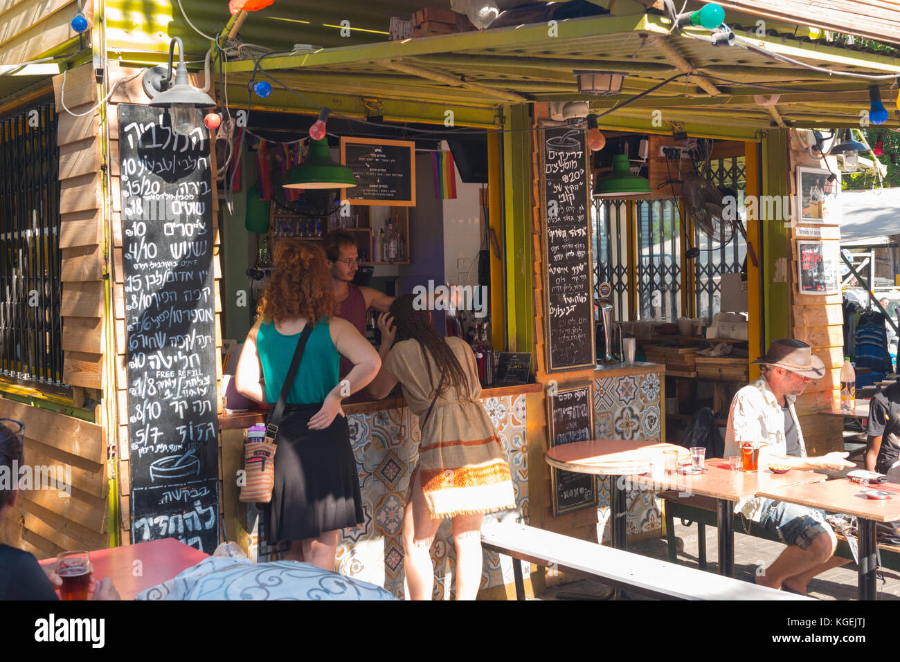 Israel The Holy Land Tel Aviv Jaffa Yafo flea market cafe bar wooden shed benches seats customers drinks glasses chalk board boards Hebrew Ivrit Stock Photo