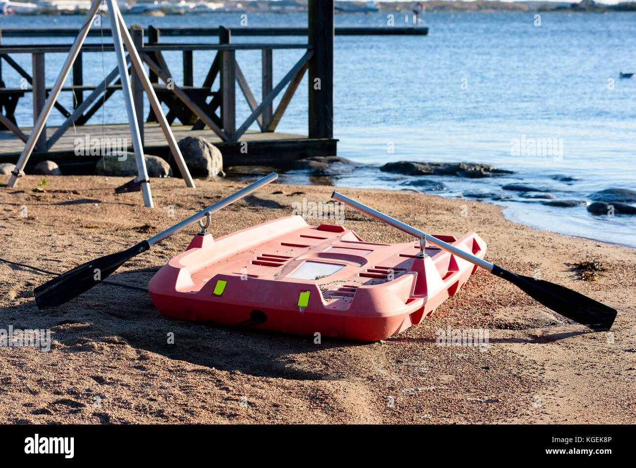 Life-saving equipment on beach. Orange plastic boat or raft with oars ready for use. Stock Photo