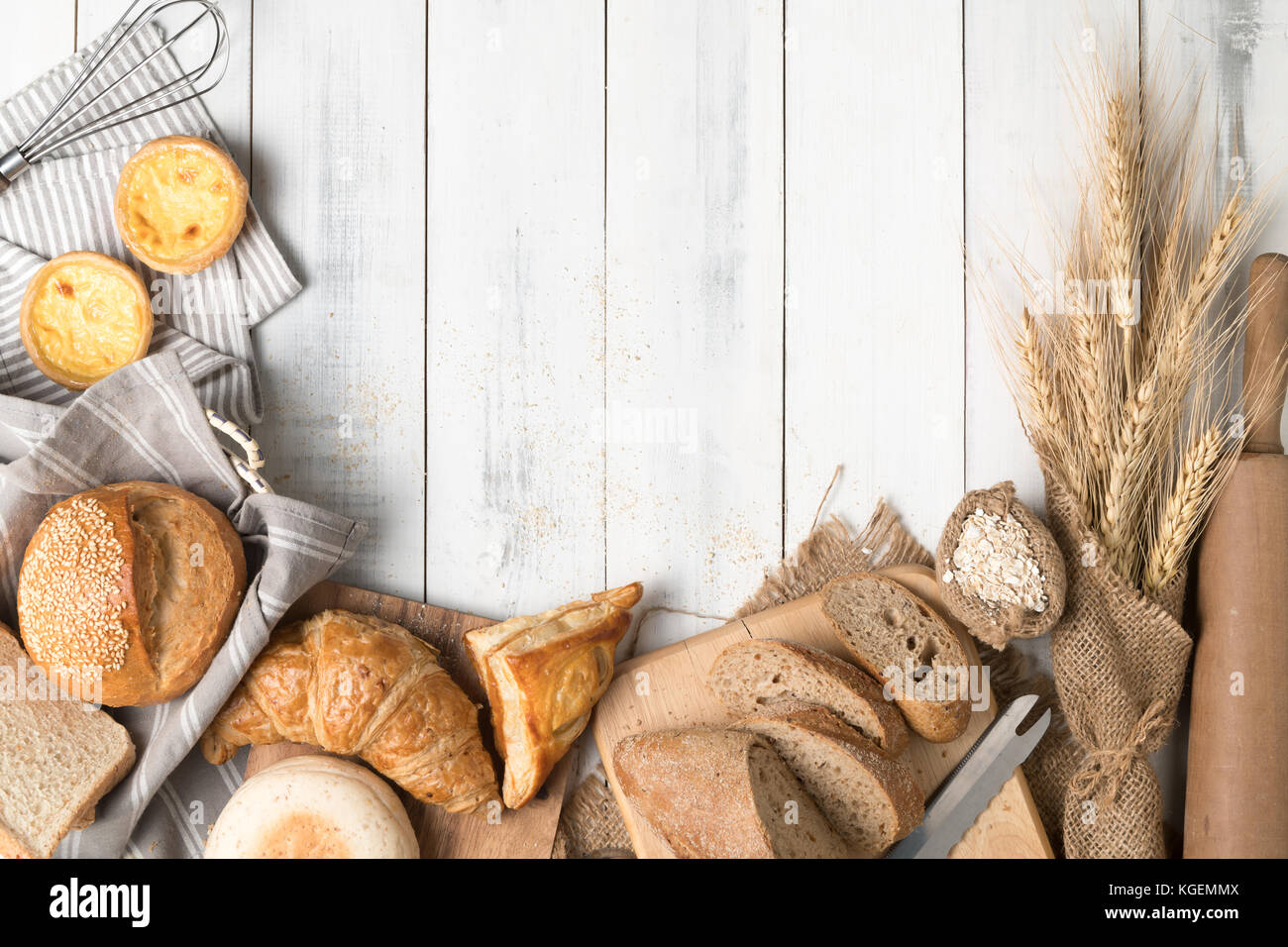 Homemade breads or bun, croissant and bakery ingredients on white wood