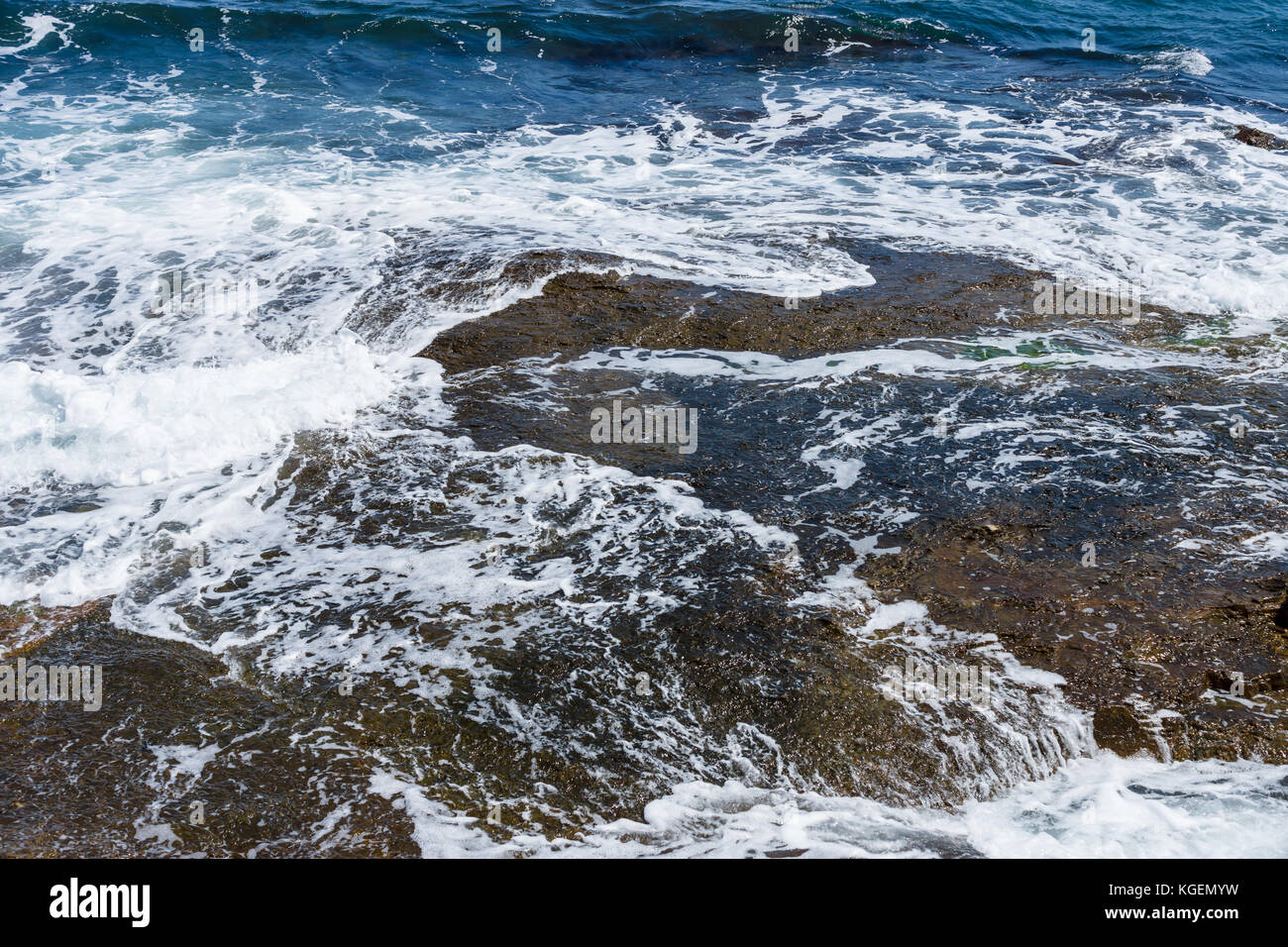 Blue sea, waves and rocky shore Stock Photo - Alamy