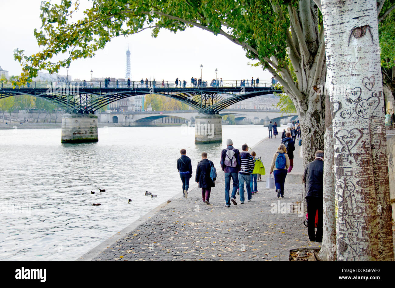 Paris, France. People walking along the north bank of the River Seine, Pont des Arts and Eiffel Tower behind Stock Photo