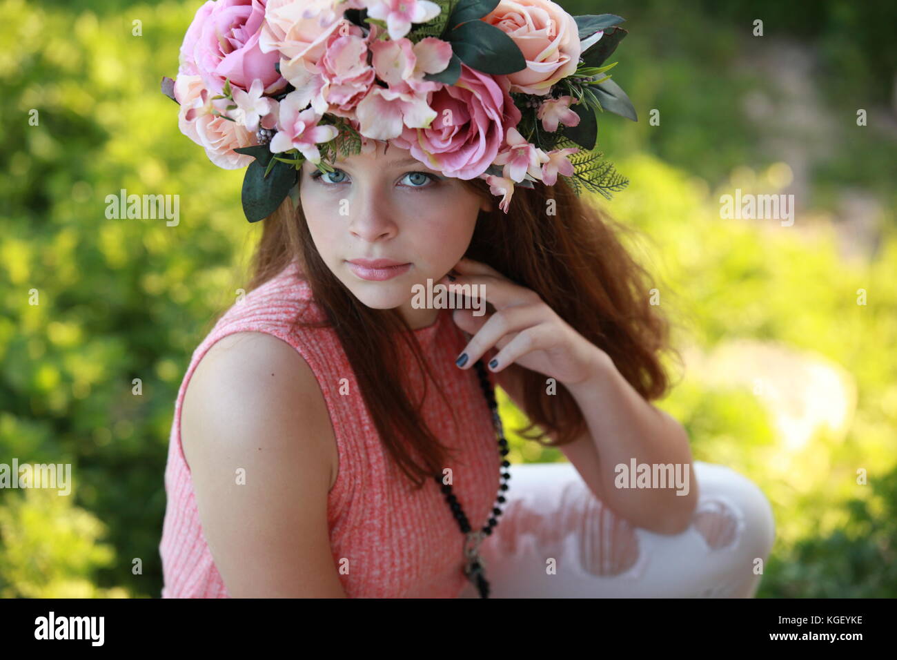 a beautiful young woman wearing a colorful flower crown and fashionable clothing in a fashion shoot looking directly at the camera Stock Photo