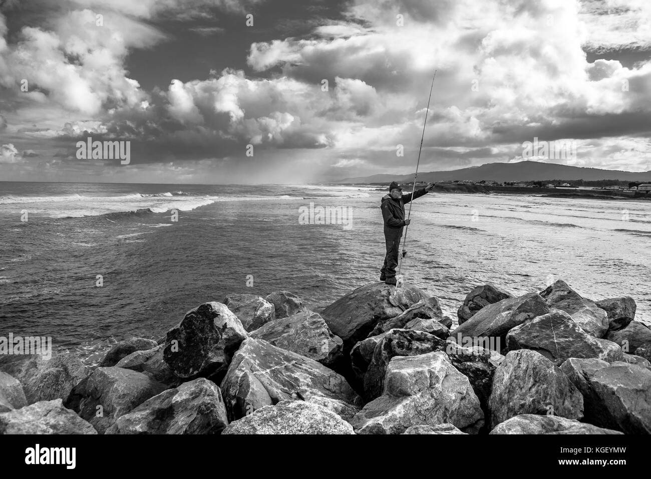 Fisherman fishing a stormy day with the sea in the background Stock Photo