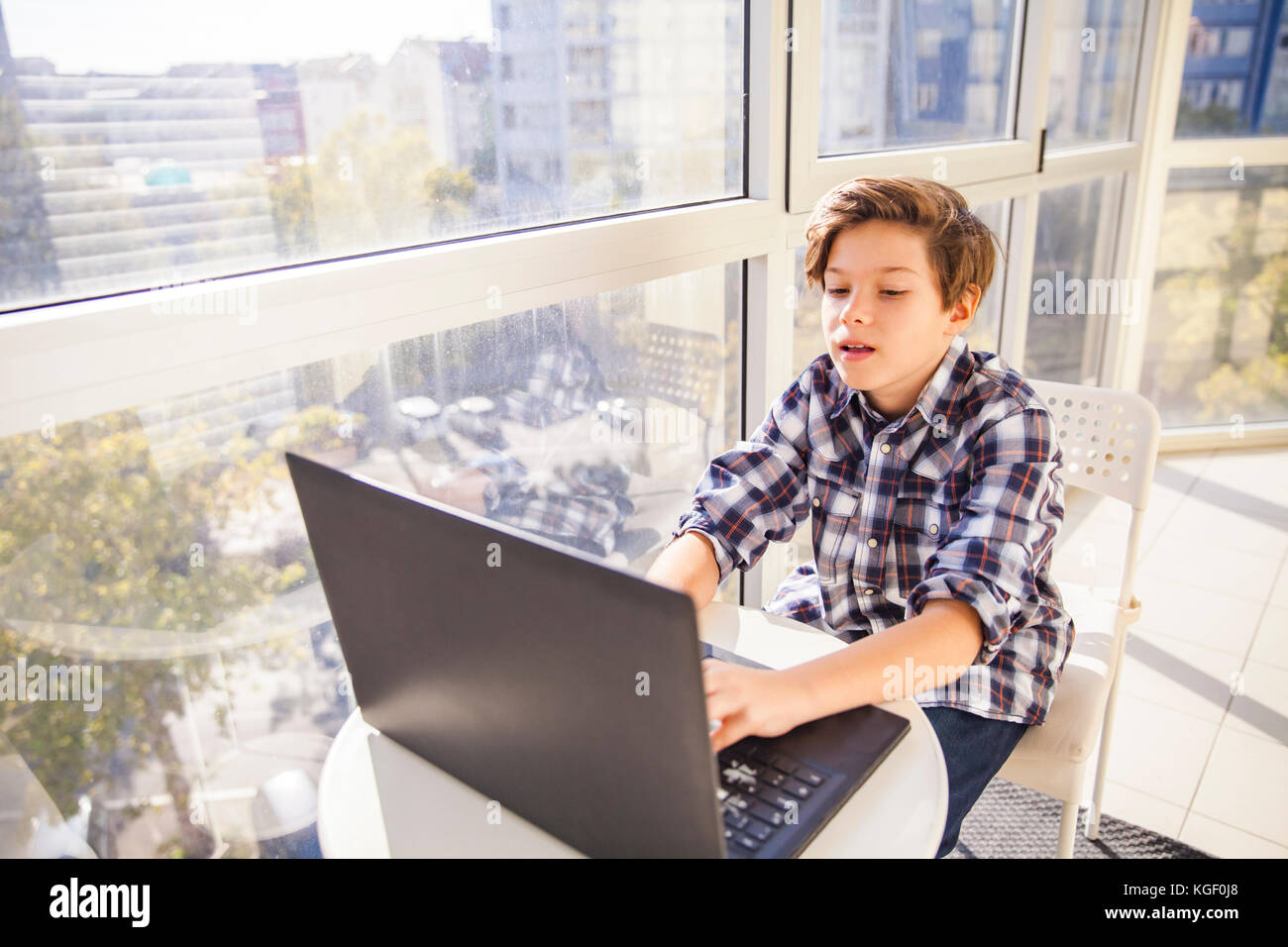 Portrait of teen boy using laptop by window Stock Photo - Alamy