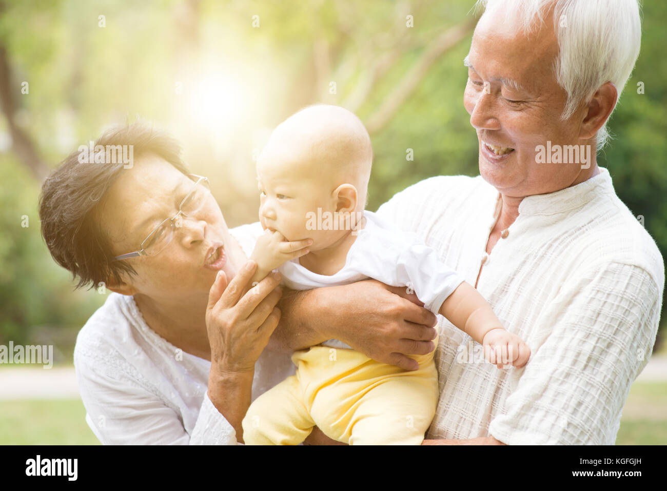 Grandparents taking care of grandchild in outdoor park. Asian family