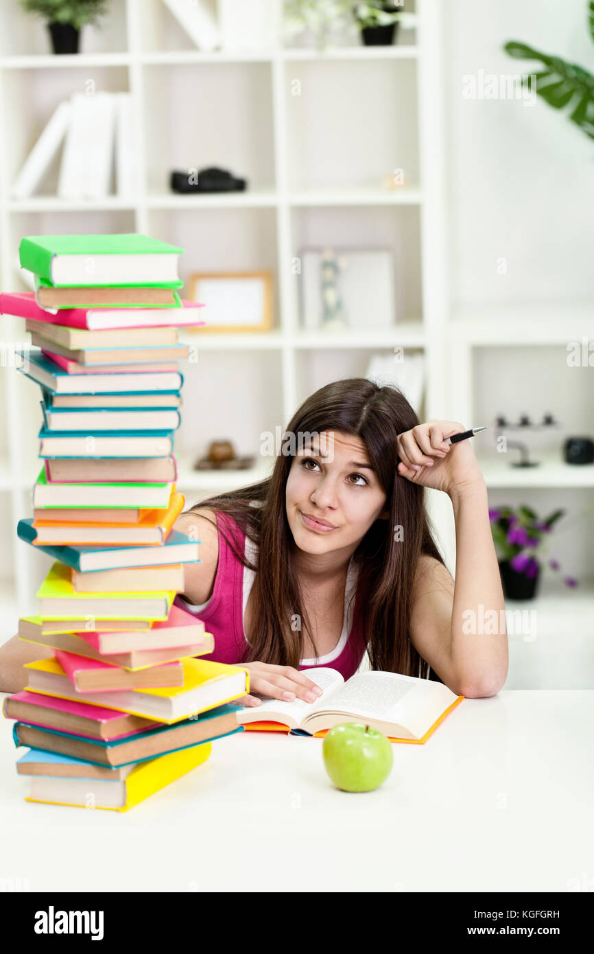 Unhappy teenage girl with big stack of books Stock Photo - Alamy