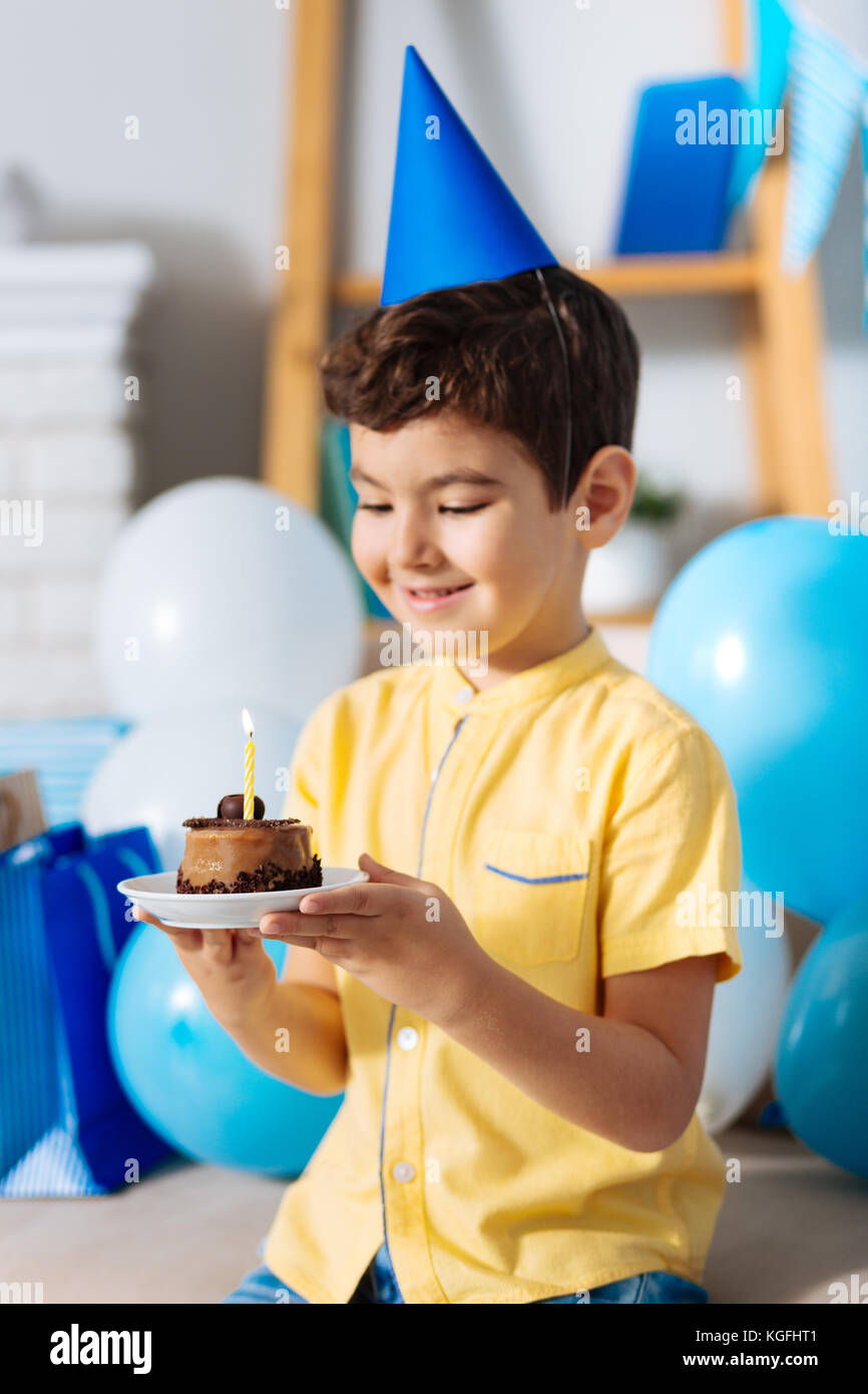 Little boy in party hat holding his birthday cake Stock Photo