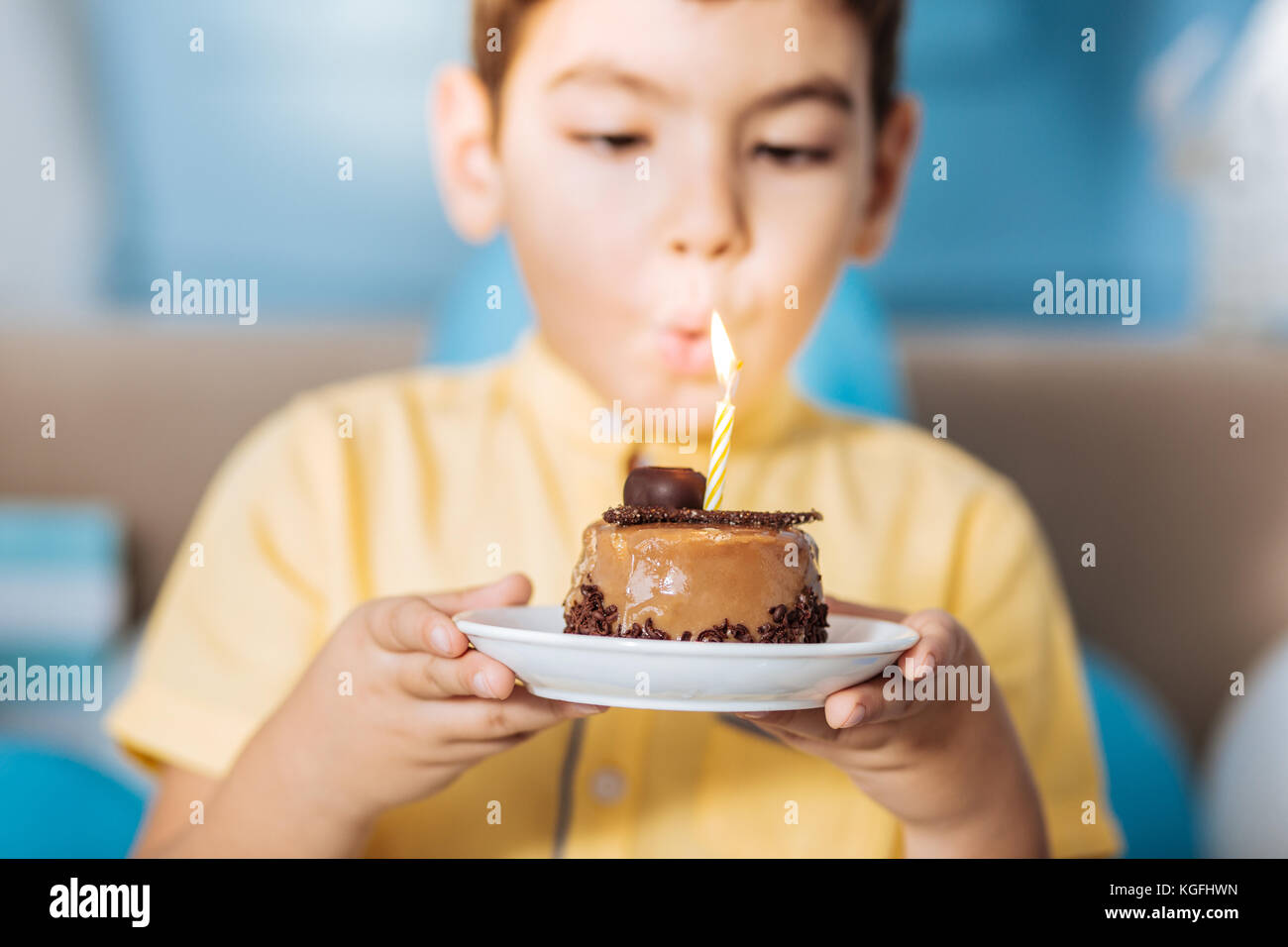 Pleasant boy blowing out candle on his cake Stock Photo Alamy