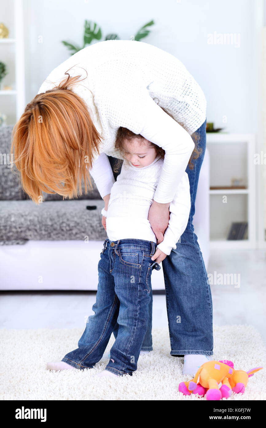 laughing mother dressing stockings her little girl Stock Photo