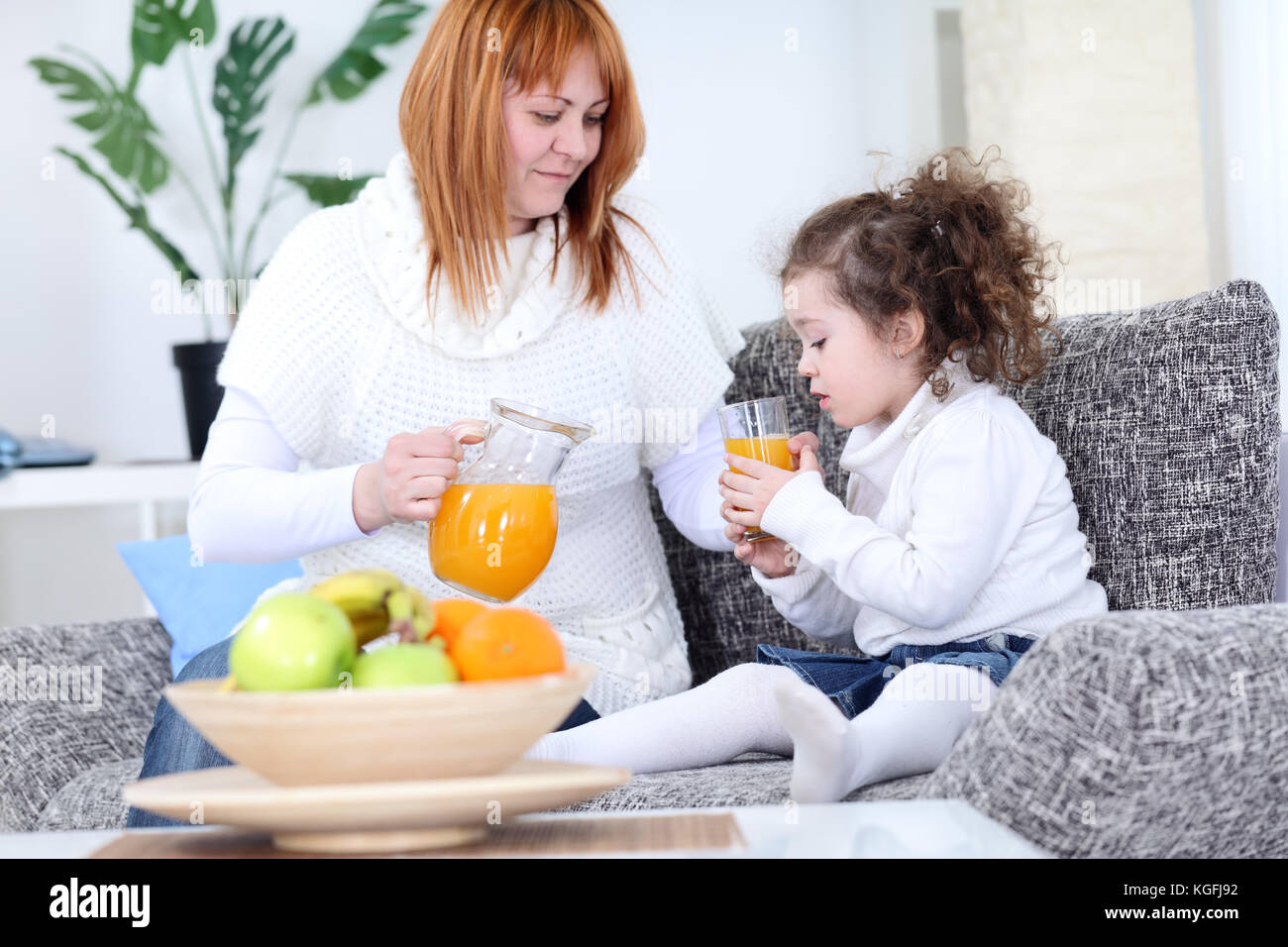mother serving orange juice her daughter Stock Photo Alamy