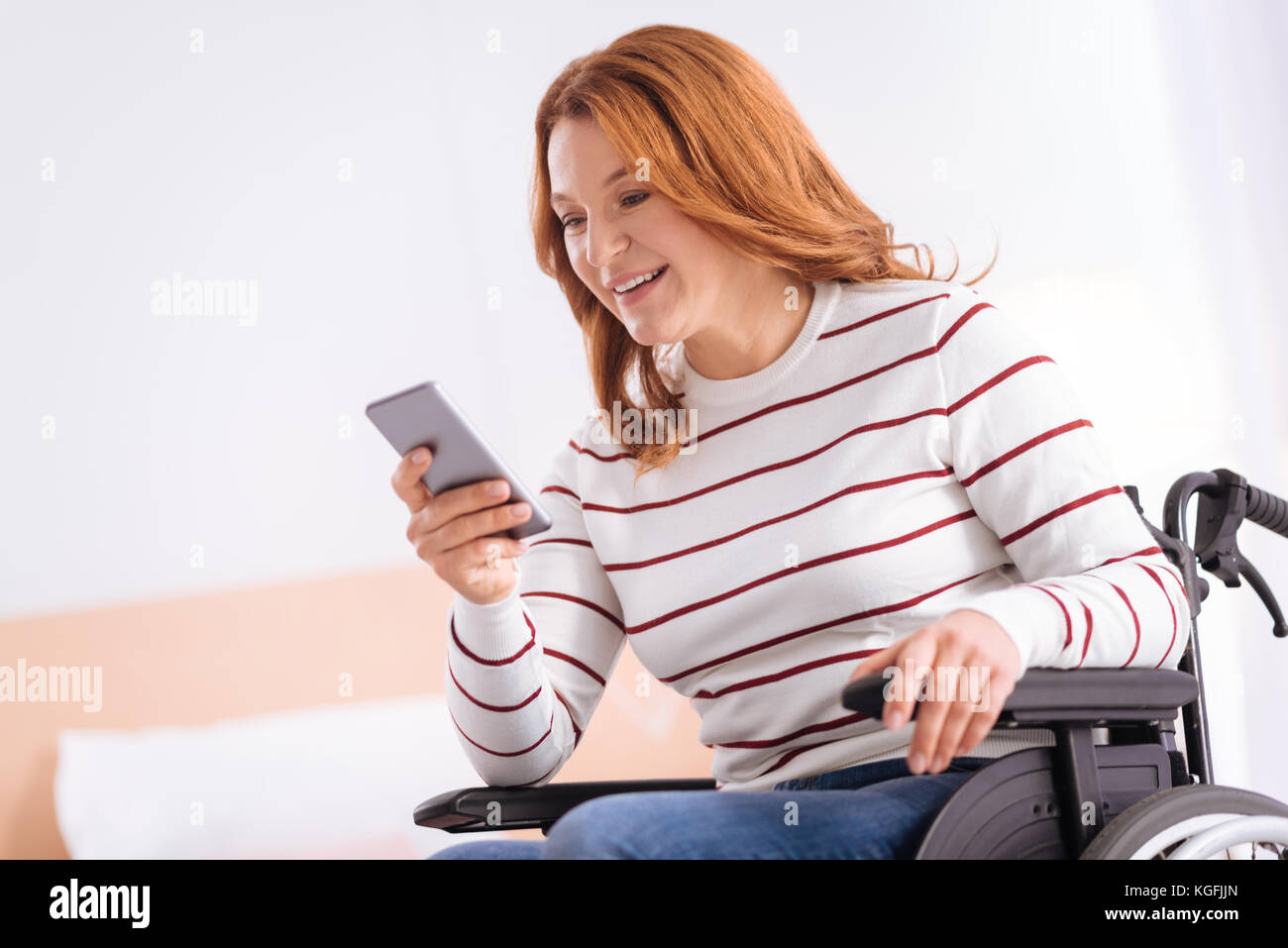 Smiling disabled woman in a wheelchair with her phone Stock Photo - Alamy