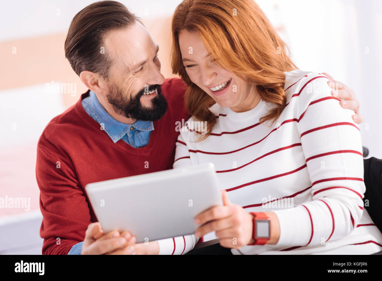 Pleased man and woman laughing while using a tablet Stock Photo