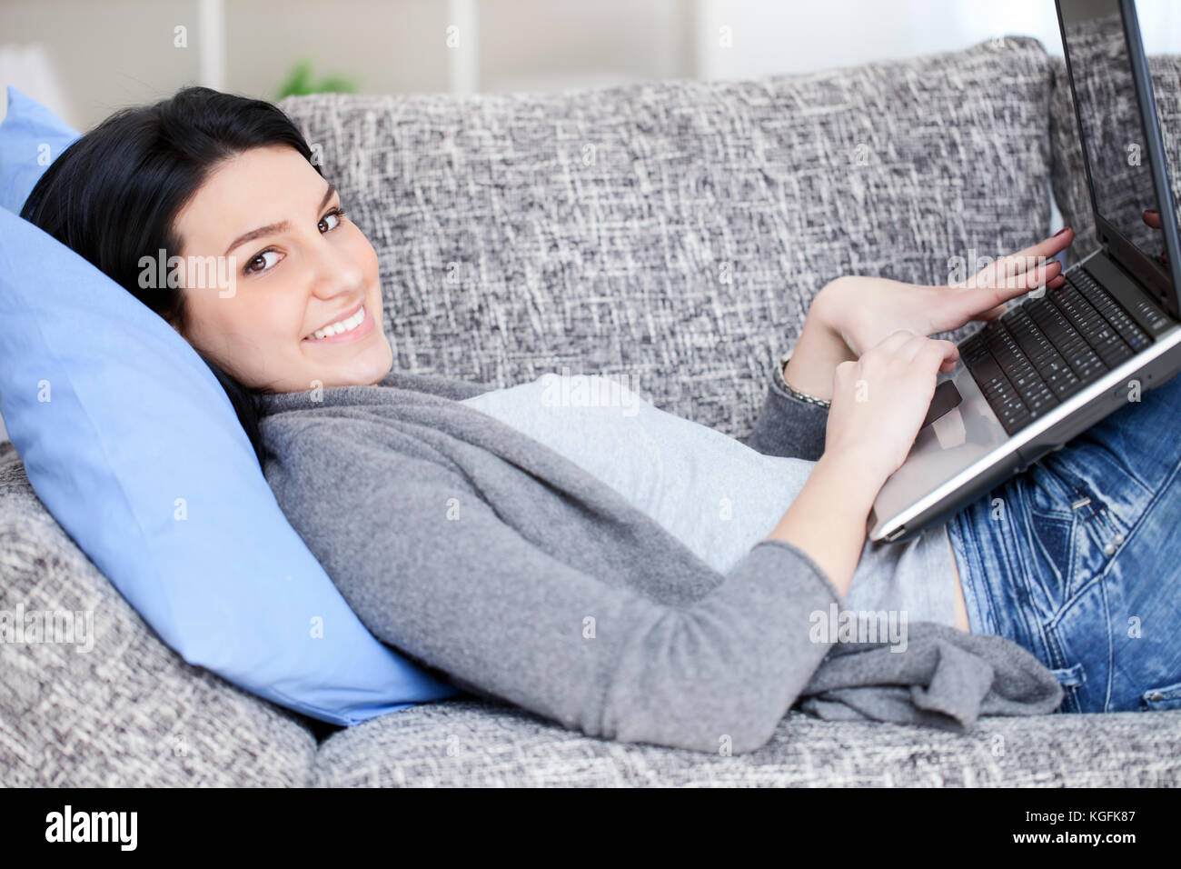beautiful cheerful woman lying on the sofa with laptop Stock Photo - Alamy
