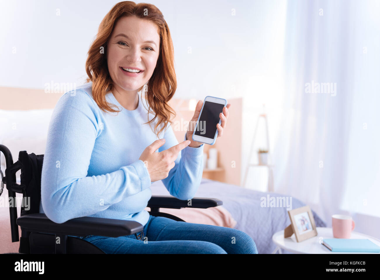Handicapped woman smiling and pointing at her phone Stock Photo - Alamy