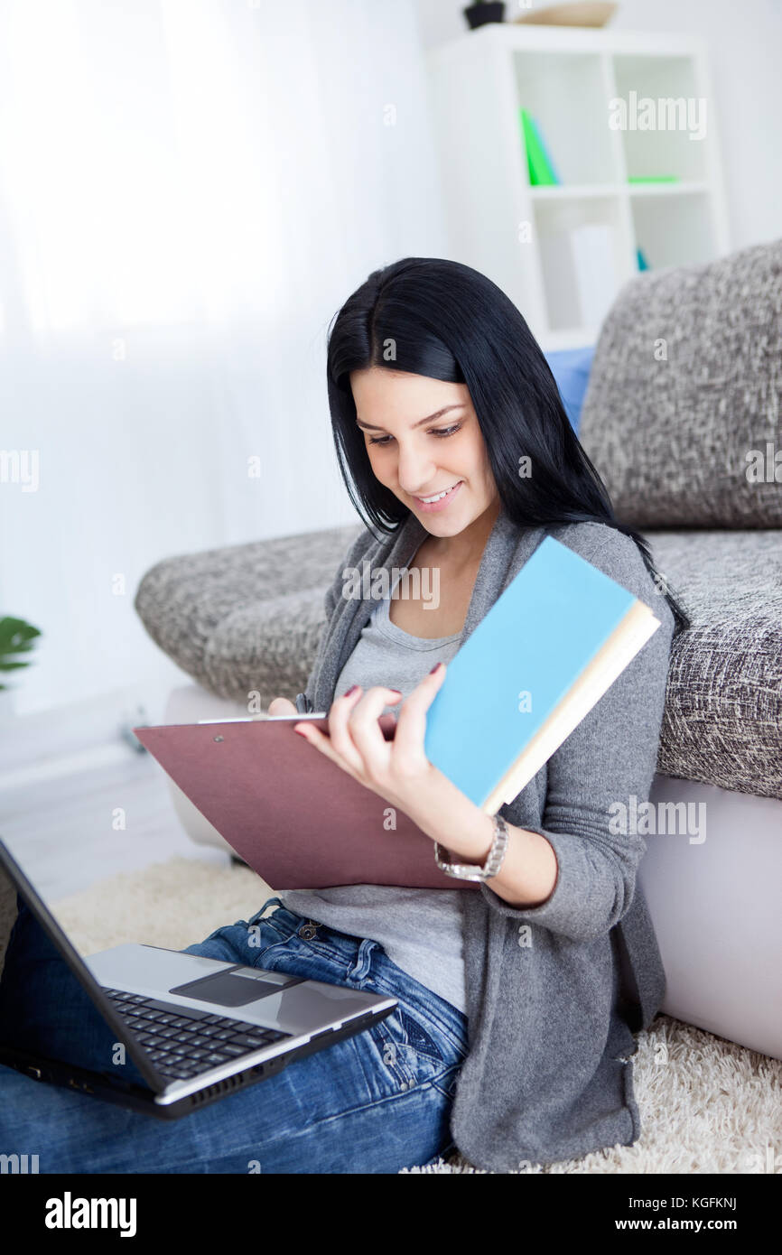 young girl with learning at home, sitting on floor and holding laptop ...