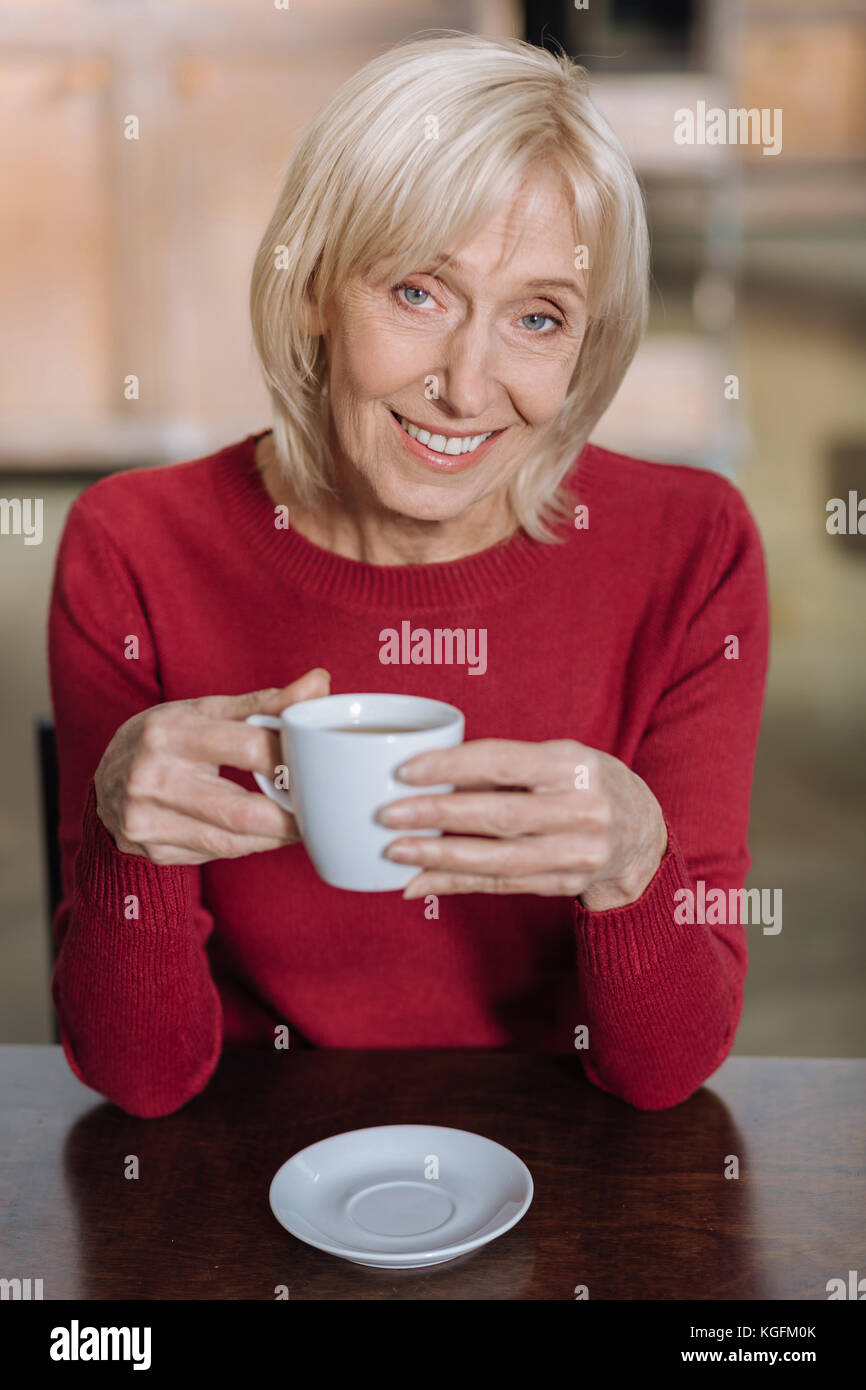 Lovely senior woman smiling happily while drinking tea Stock Photo - Alamy