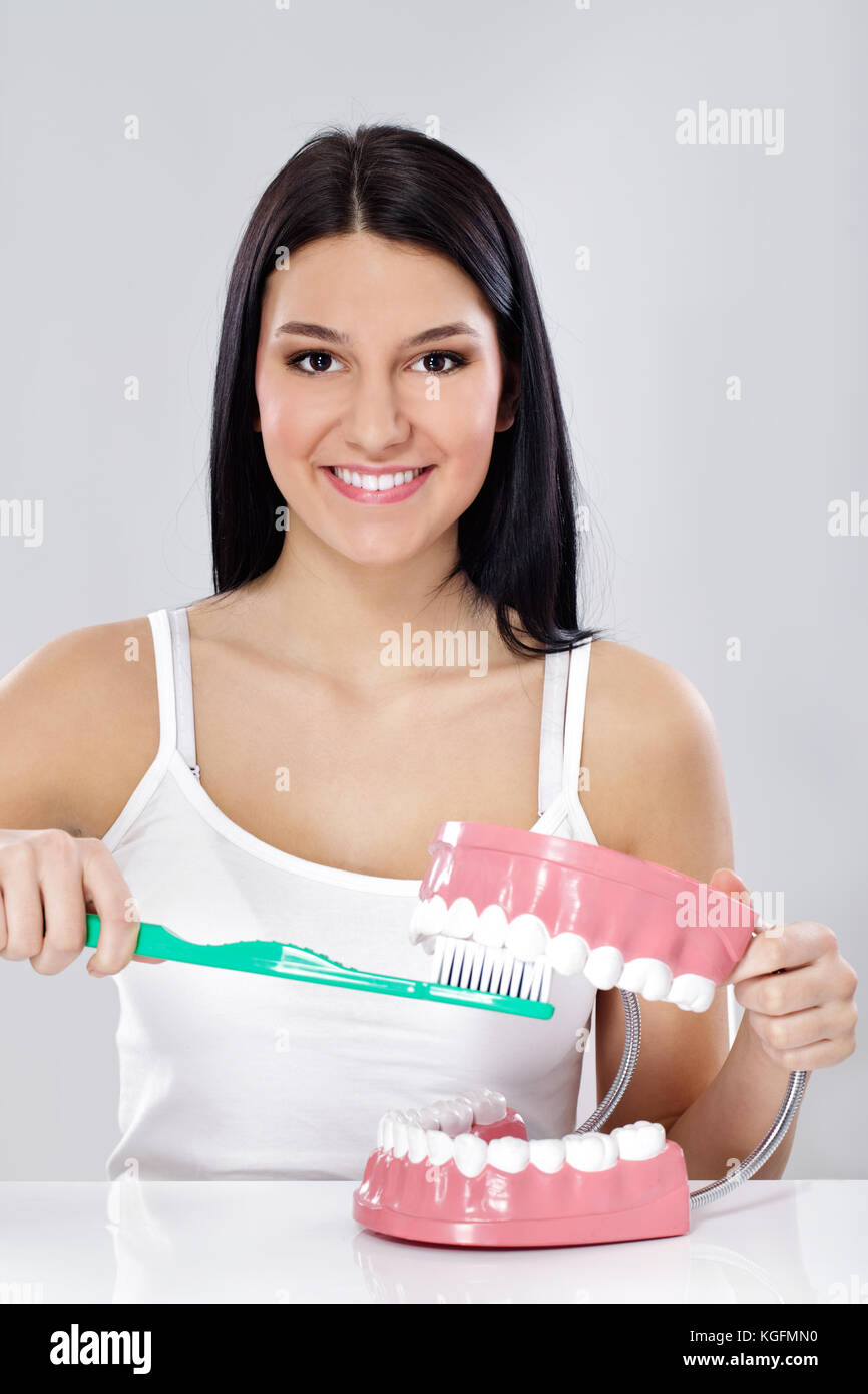 Young girl showing right way to brushing your teeth with big toothbrush
