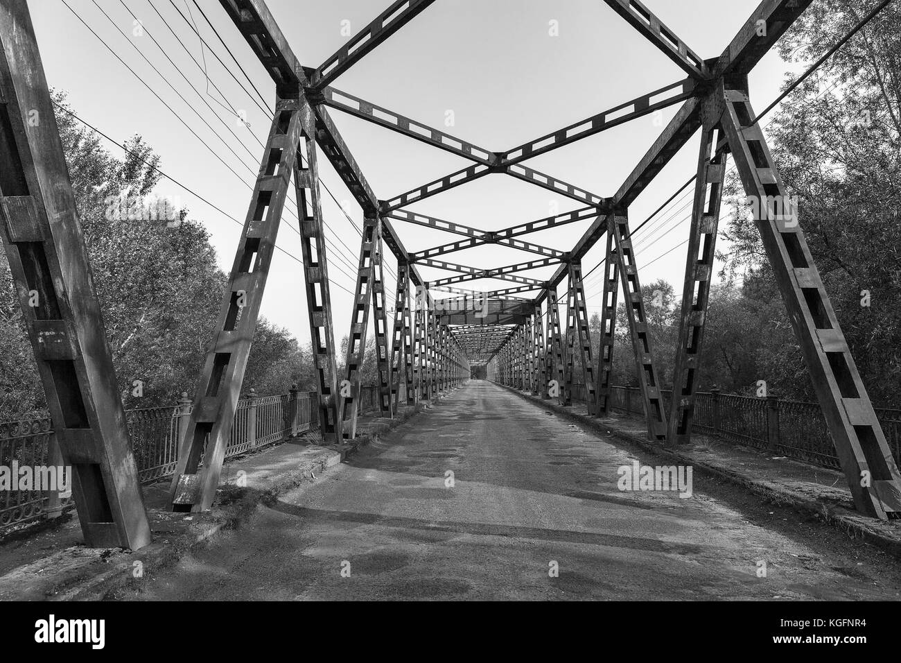 Old rusty empty bridge over Tisa river in Vylok, close to border with Hungary. It is a village in western Ukraine, Zakarpattia region. Black and white Stock Photo