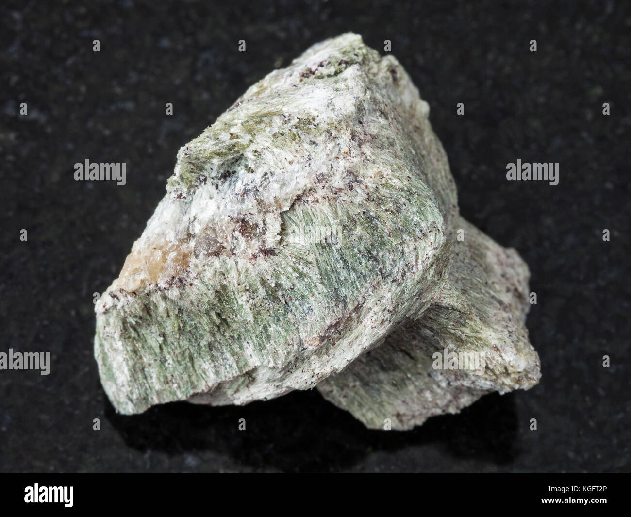 macro shooting of natural mineral rock specimen - rough richterite stone on dark granite background from Kovdor region, Kola Peninsula, Russia Stock Photo