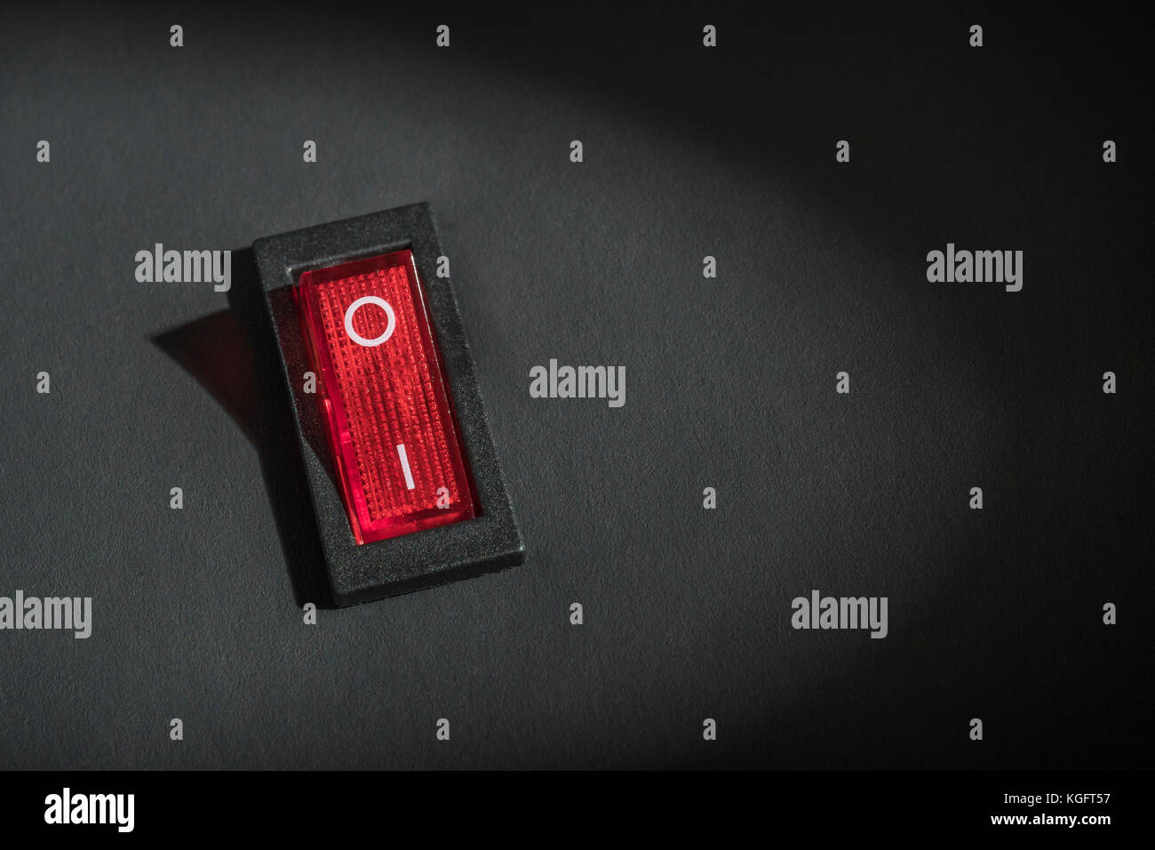 Illuminated red electrical switch on black background potential