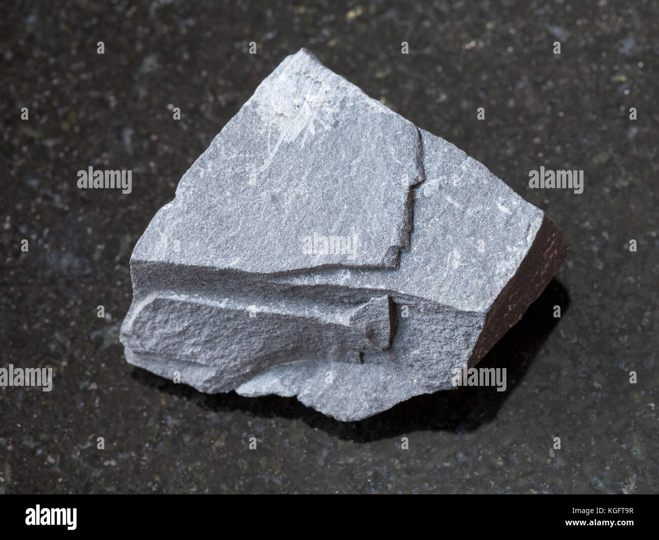 macro shooting of natural mineral rock specimen - rough argillite stone on dark granite background Stock Photo