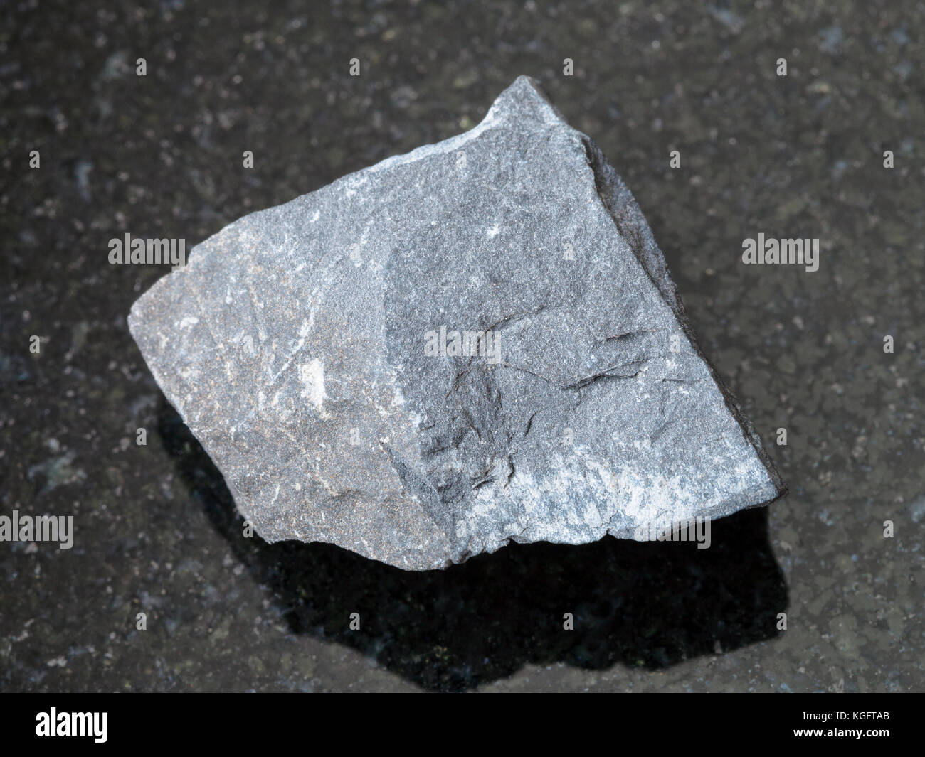 macro shooting of natural mineral rock specimen - raw argillite stone on dark granite background Stock Photo