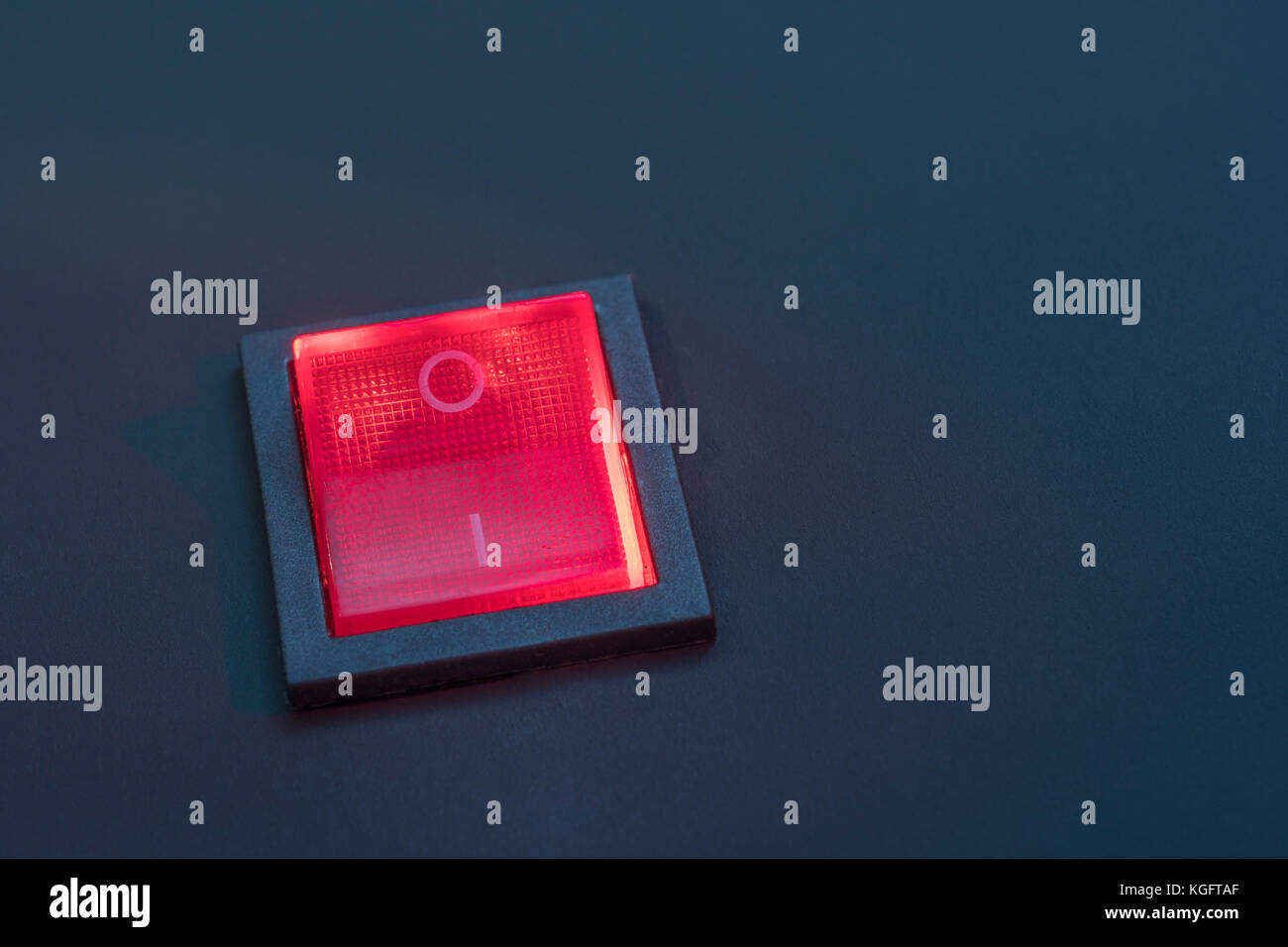 Illuminated red electrical switch on black background potential