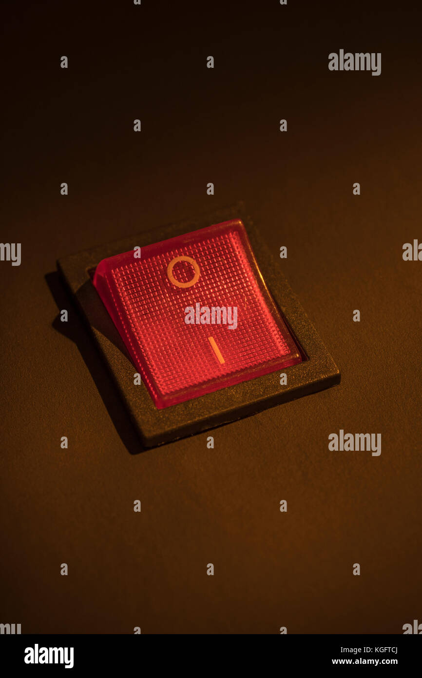 Illuminated red electrical switch on black background potential