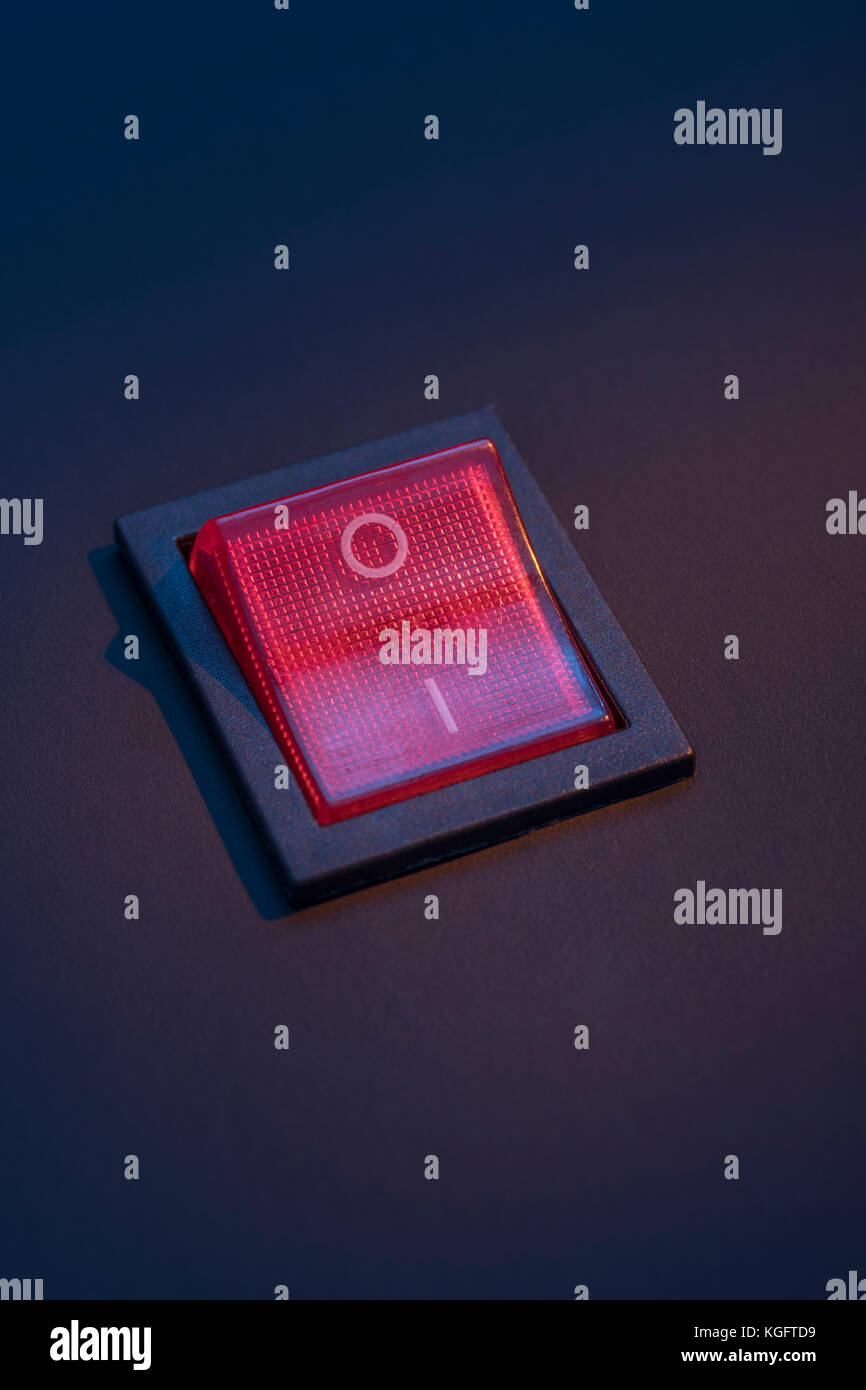 Illuminated red electrical switch on black background potential
