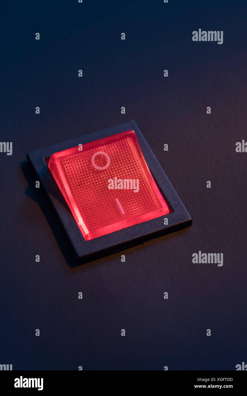 Illuminated red electrical switch on black background potential