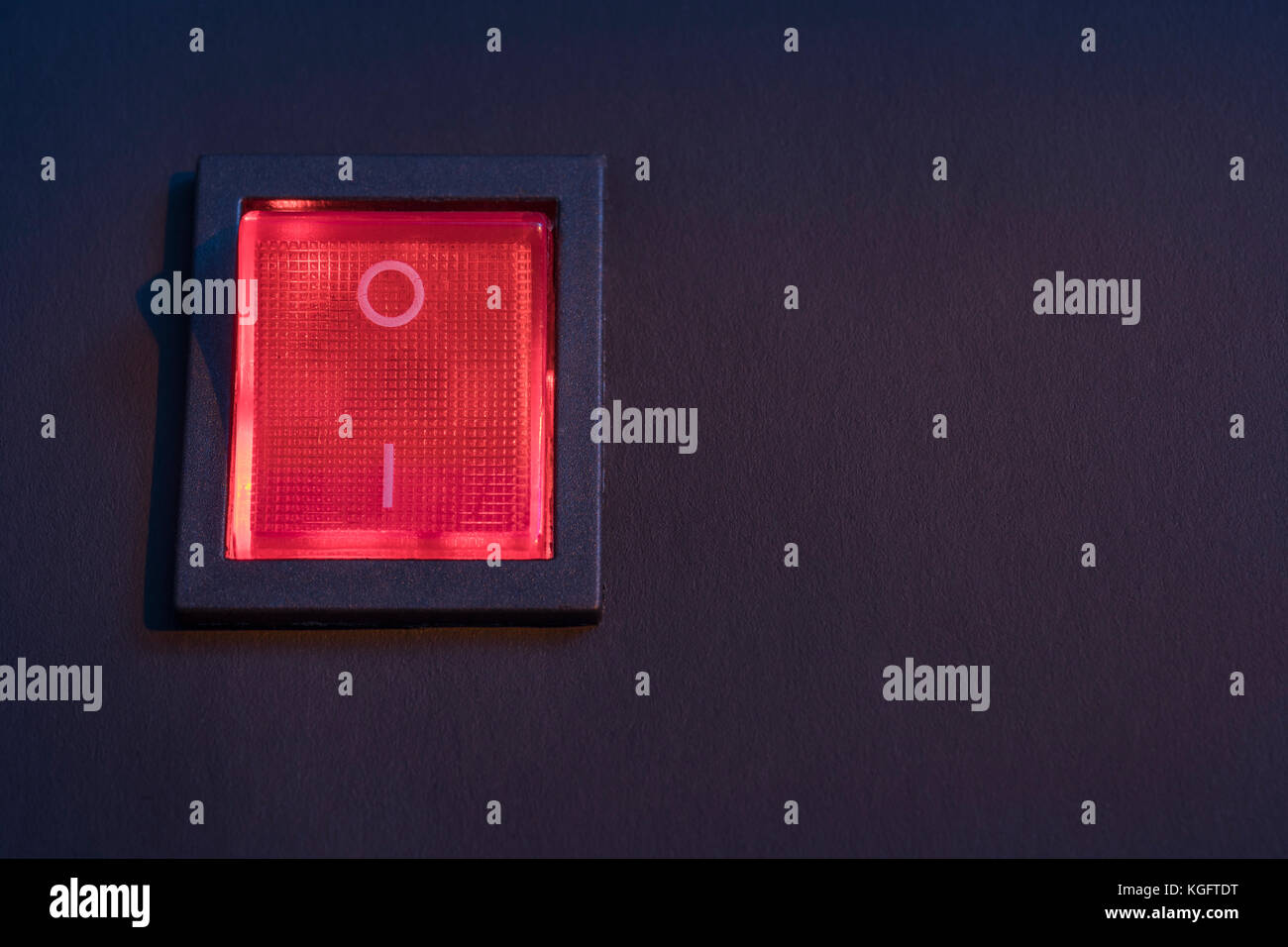 Illuminated red electrical switch on black background potential