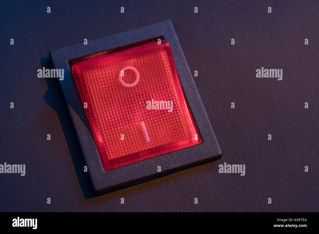 Illuminated red electrical switch on black background potential